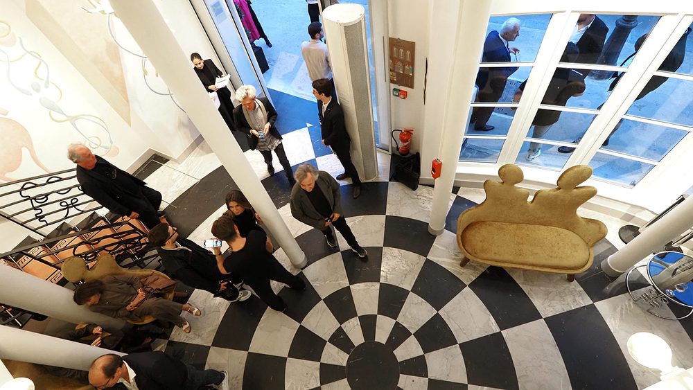 Hall de l'hôtel Le Magnifique, sol en damier noir et blanc et banquette sculptée, soirée d'inauguration