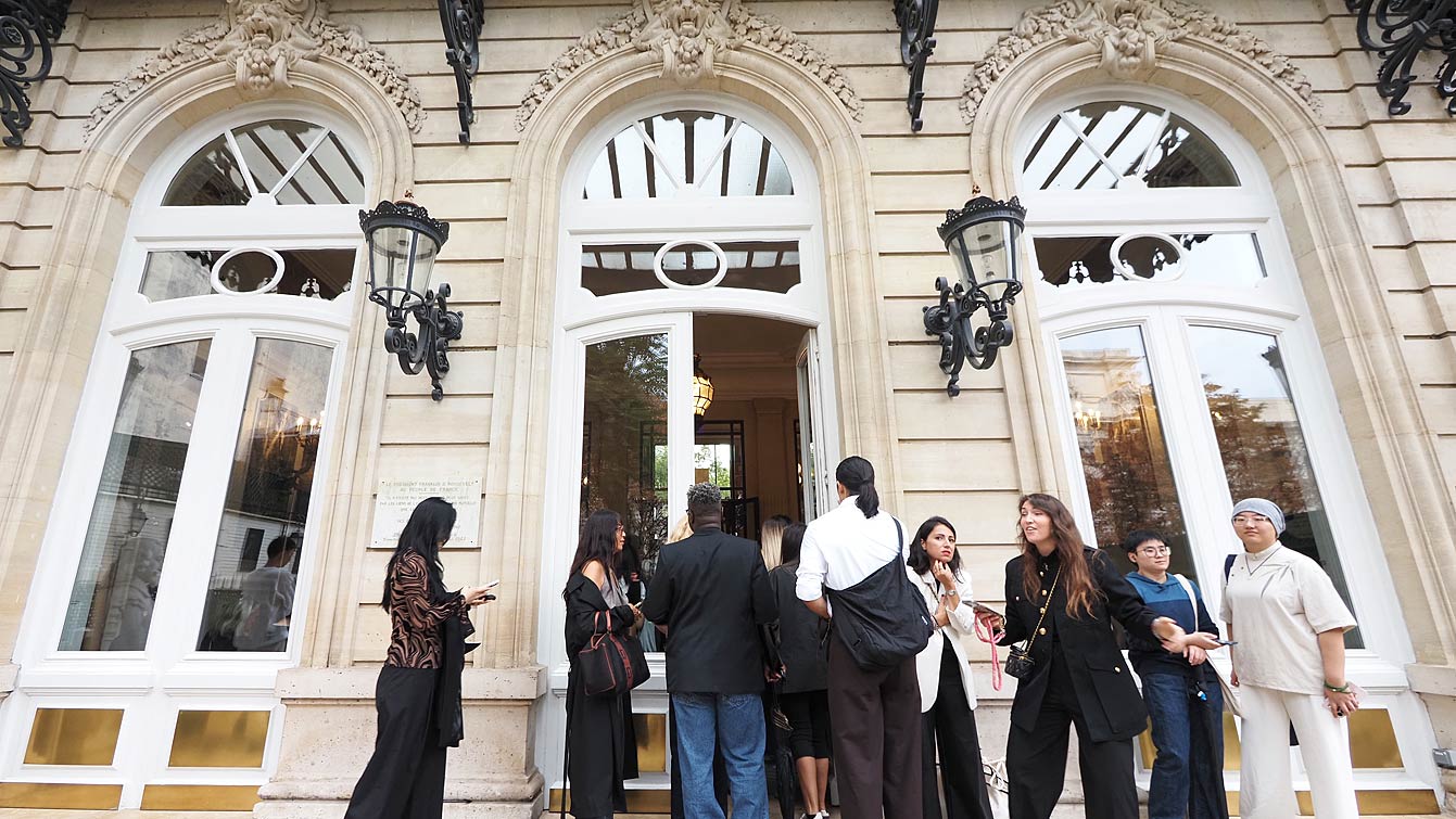 Invités réunis devant l'entrée de l'Hôtel Le Marois, façade en pierre avec portes-fenêtres cintrées et lanternes en fer forgé, avenue Franklin Delano Roosevelt à Paris, avant le défilé NEXT ASIA