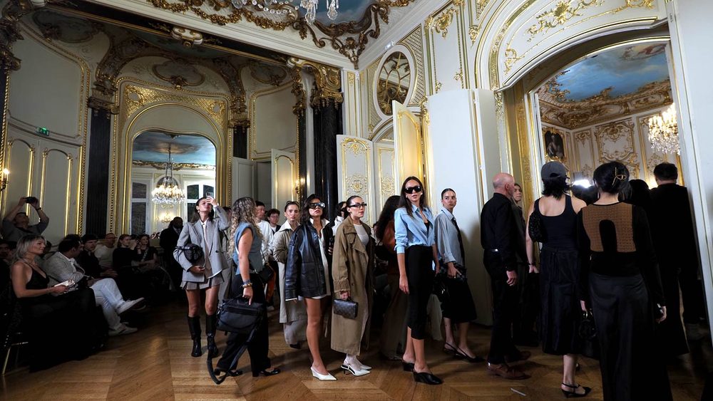 Invités élégamment habillés traversant les salons blanc et or de l'Hôtel Le Marois pour s'installer avant le défilé NEXT ASIA, pendant la Paris Fashion Week
