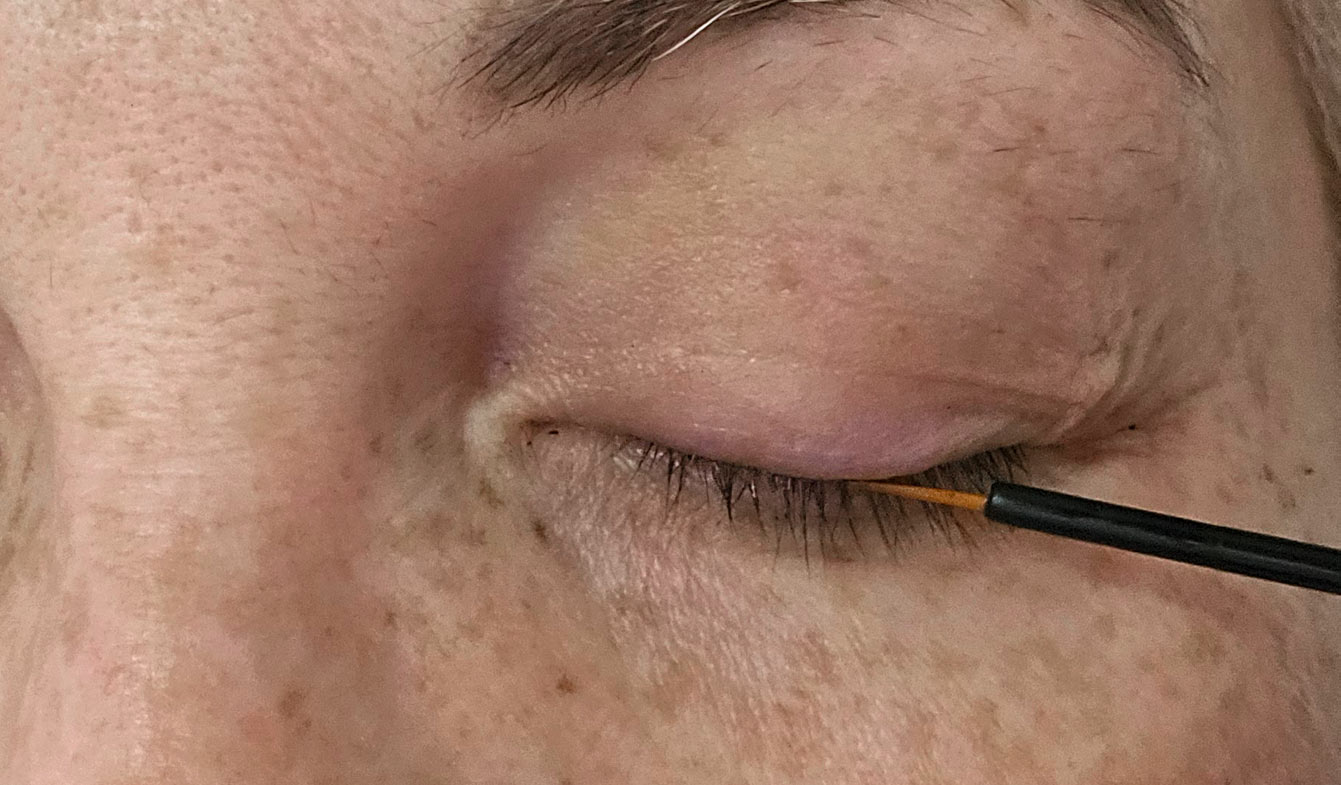 Application du sérum RevitaLash au pinceau à la base des cils supérieurs