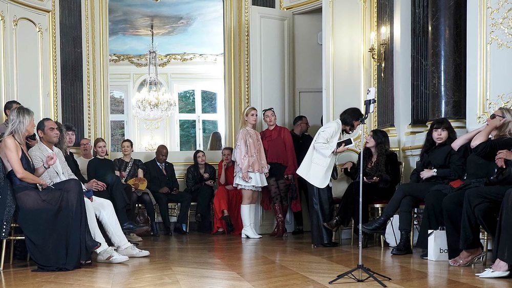 Invités bien habillés prenant place au fond d'un salon de l'Hôtel Le Marois, avant le début du défilé NEXT ASIA