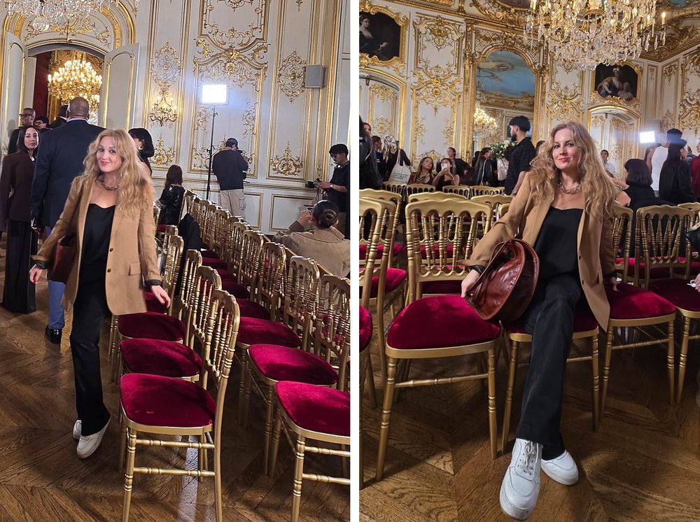 Femme blonde en blazer camel, tenue noire et baskets blanches, debout entre les rangées de chaises dorées en velours rouge de l'Hôtel Le Marois, avant le défilé NEXT ASIA