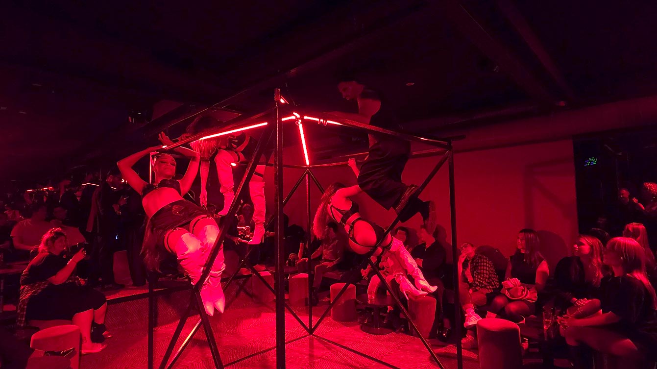 Danseuses suspendues à une cage métallique sous lumière rouge lors du Freak Show au Zouzou Pigalle.