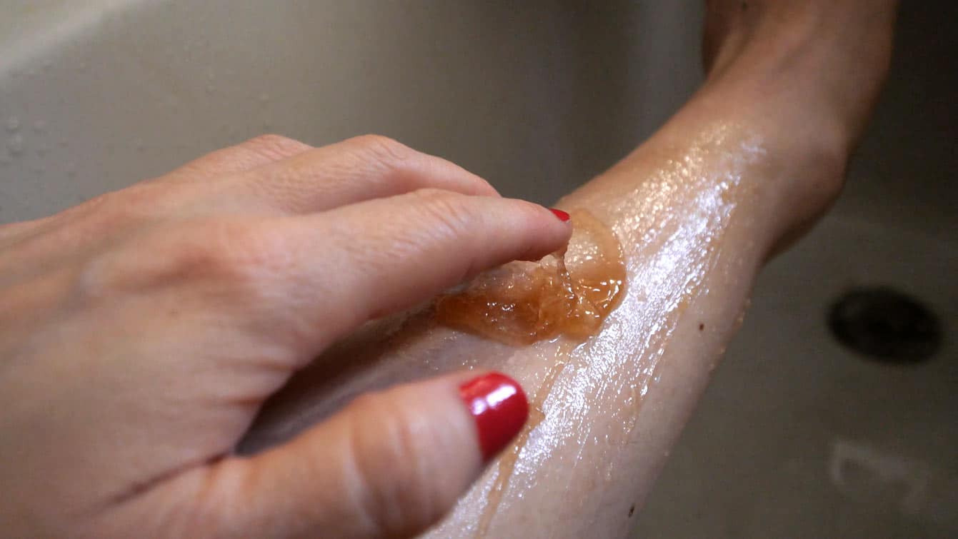 application du gommage sur la jambe